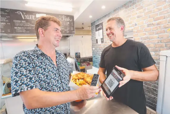  ?? Picture: RICHARD GOSLING ?? 7th Avenue Fish & Chips owner Kyle Tinsley with customer Pete Whelan (left) buying some fish and chips with cryptocurr­ency ethereum.