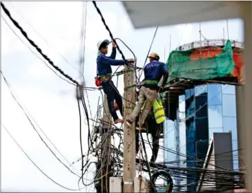  ?? HENG CHIVOAN ?? Electricia­ns maintain power lines on Monivong Blvd in the Chamkarmon district on August 10.