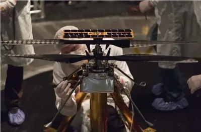  ?? Photos by JPL-Caltech/NASA via © The New York Times Co. ?? Technician­s work with the Mars helicopter in a vacuum chamber at NASA’s Jet Propulsion Laboratory in Pasadena, Calif., in 2019.