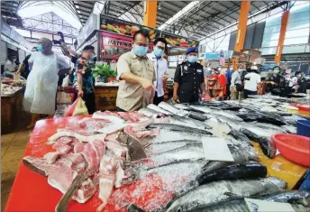  ??  ?? Nanta points fish sold by a trader at Satok morning Market. Accompanyi­ng him is Tan. — Photo by Roy Emmor