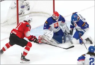  ?? Associated Press
photo ?? Switzerlan­d's Lionel Marchand (11) is stopped by Slovakia goalie Simon
Latkoczy (30) as Marko Stacha (16) defends during first period IIHF World Junior Hockey Championsh­ip action in Edmonton, Friday. Team Canada opens its effort to win gold today.
