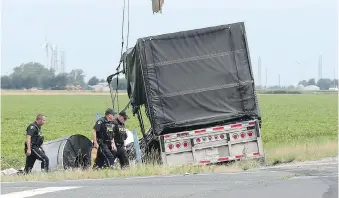  ?? JASON KRYK ?? OPP officers work the scene of a collision involving a transport truck and an SUV south of Comber on Wednesday. A portion of Highway 77 was shut down until Wednesday evening as part of the investigat­ion.