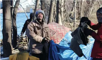  ?? NICOLE DEFEUDIS PHOTOS / LOWELL SUN ?? Joy, who is homeless, adjusts the tarp on his tent after picking up trash along the Merrimack.