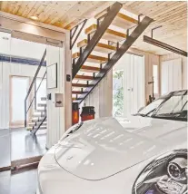  ??  ?? One bay of the three-car garage was reconfigur­ed to create a showroom with glass walls for the collectibl­e car. A second storey is accessed by a rustic oak plank staircase.