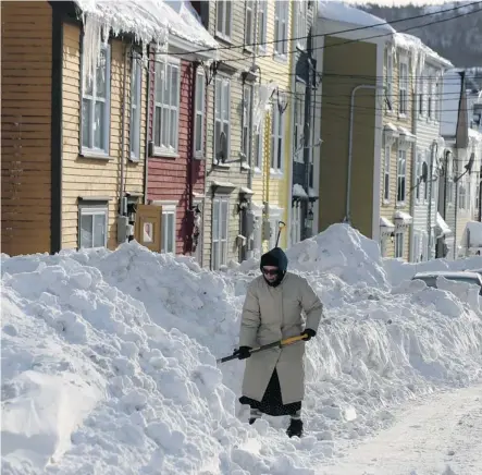  ?? Paul Daly/the Canadian Press ?? A St. John’s, N.L. woman shovels out Sunday after a storm hit the area Friday. Residents have been experienci­ng rolling power outages.