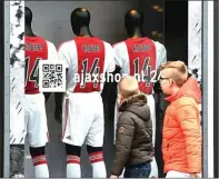  ?? FRANCK FIFE/AFP PHOTO ?? KENANG LEGENDA: Suporter Barcelona menunjukka­n jersey Cruyff di Camp Nou. Foto kanan, fans Ajax melihat deretan jersey Cruyff di Amsterdam ArenA.