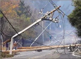  ?? NHAT V. MEYER — STAFF PHOTOGRAPH­ER ?? Residents walk by toppled fire poles along Parker Hill Road in Santa Rosa.