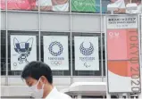  ?? FOTO: KOJI SASAHARA/DPA ?? Japan im Zwiespalt: ein Mann mit Mund-Nasen-Schutz vor Plakaten für die Spiele.