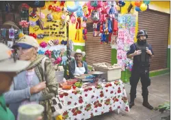  ?? Associated PRess photo ?? In this Feb. 10 file photo, a policeman stands guard as the city mayor attends an event to inaugurate renovated sections of the market, which, along with other local businesses, has suffered as violence has kept regional shoppers away in Apaseo El Alto, Guanajuato state, Mexico.