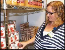  ??  ?? Dr. Melissa Jefferis of OhioHealth Riverside Family Medicine Practice Center in Columbus, looks over the office’s stock of canned goods that it distribute­s to foodinsecu­re, diabetic patients as part of its Food is Health program.