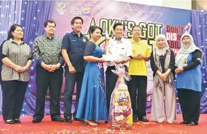  ??  ?? TAHNIAH: Lee menyampaik­an hadiah kemenangan kepada Roffina yang menjadi juara Kategori Nyanyian Solo ‘OKU’s Got Talent’ sambil disaksikan (dari kiri) Elizabeth, Abdul Aziz, Dennis, Sebastian, Armisy dan Sharifah.