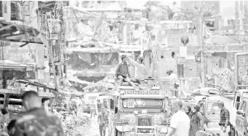  ??  ?? Residents on top of their jeepney take photos of destroyed buildings during a visit to their homes at the main battle area in Marawi City, in southern island of Mindanao. — AFP photo