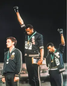  ?? Associated Press 1968 ?? U. S. athletes Tommie Smith ( center) and John Carlos extend gloved hands skyward at the Mexico City Olympics.