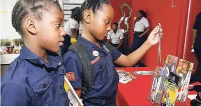 ?? LIONEL ROOKWOOD/PHOTOGRAPH­ER ?? Vitanya Allen (left) and Jazmyne Treasure, both of Ensom City Primary School, look at fire-safety brochures that were on display during the launch of Fire Safety Awareness Week held at Spanish Court Hotel, St Andrew, recently.