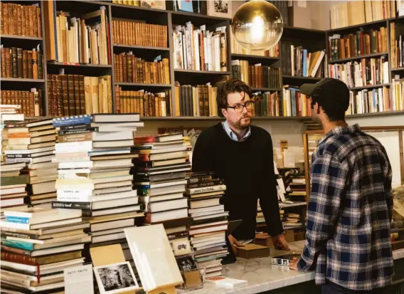  ?? PHOTOS BY LAURA MORTON ?? Andrew Sivak, co-owner of Bad Animal, helps a customer at the business in downtown Santa Cruz. The independen­t bookstore is also a natural wine bar and restaurant.