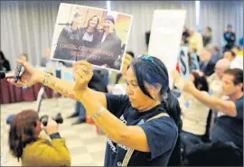  ?? Michael Owen Baker
For The Times ?? VENICE RESIDENT Lydia Ponce holds a photo of California Coastal Commission­er Wendy Mitchell and David Evans of the band U2 at the March 10 meeting.