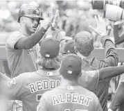  ?? Karen Warren / Houston Chronicle ?? Carlos Correa, left, is welcomed back to the Astros dugout after scoring on Evan Gattis’ seventh-inning single on Sunday at Globe Life Park.