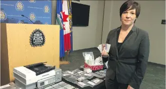  ?? CLARA
HO/ CALGARY
HERALD ?? Staff Sgt. Kristie Verheul with the Calgary Police Service’s economic crimes unit shows off blank cards, printers and other equipment on Wednesday, seized from a southeast home in connection with a credit card and identifica­tion counterfei­ting operation.