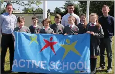  ??  ?? Kerry’s Shane Enright about to raise the Active Schools flag at Dromclough NS with the student Active Schools Committee and teachers Kevin Enright and Kevin Stack.