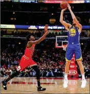  ?? ASSOCIATED PRESS ?? GOLDEN STATE WARRIORS guard Klay Thompson (right) shoots a three-pointer against Chicago Bulls forward Justin Holiday (left) during the first half of Monday’s game in Chicago.