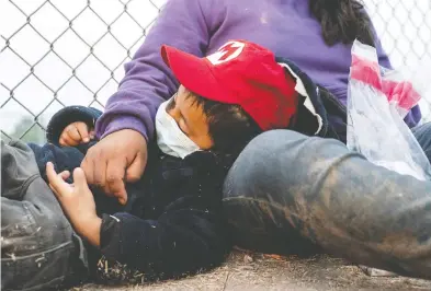  ?? GO NAKAMURA / REUTERS ?? Misael, a 4-year-old asylum-seeking migrant child from Guatemala, sleeps on the ground near his mother Anna while waiting to be transporte­d by U.S. Border Patrol in La Joya, Texas, earlier this month.