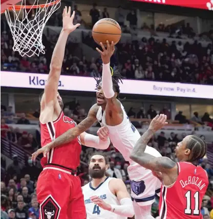  ?? AP ?? Grizzlies MVP candidate Ja Morant, who scored a career-high 46 points, shoots between Nikola Vucevic and DeMar DeRozan.