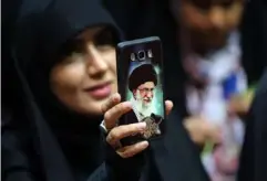  ?? (AFP/Getty) ?? At a rally in the capital, an Iranian woman shows her phone cover depicting Khamenei