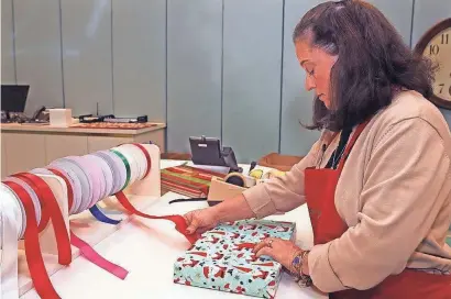  ?? ANGELA PETERSON/MILWAUKEE JOURNAL SENTINEL ?? Caryn Lisowski, customer service manager at Von Maur at The Corners of Brookfield, takes pride in the department store's free gift wrapping for customers. To see a video, go to jsonline.com/business.