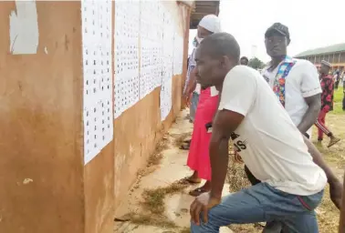  ??  ?? Some voters. checking for their names on INEC’S register at Ughiele primary school, Aviele