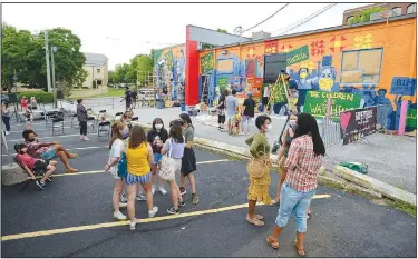  ?? (NWA Democrat-Gazette/Andy Shupe) ?? Residents watch Saturday as Art Ventures artists complete a mural during the Fayettevil­le in Living Color event in the parking lot of St. Paul’s Episcopal Church in Fayettevil­le. The event was held to register residents to vote, to support the Black Lives Matter movement and to foster community unity. Visit nwaonline.com/200621Dail­y/ for today’s photo gallery.