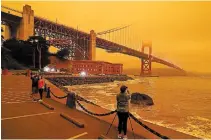  ?? ERIC RISBERG THE ASSOCIATED PRESS ?? People stopped to take pictures of an orange sky over the Golden Gate Bridge caused by heavy smoke in September.