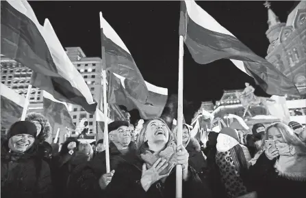  ?? PAVEL GOLOVKIN
THE ASSOCIATED PRESS ?? People wave Russian flags Sunday as they wait for election results in Manezhnaya square, near the Kremlin in Moscow.