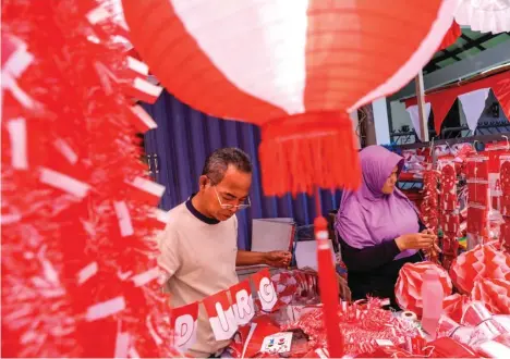  ?? DIPTA WAHYU/JAWA POS ?? BERKAH TAHUNAN: Nurcholis Arifin menata daganganny­a. Memasuki Agustus, penjualan bendera dan aksesori lainnya naik 3-4 kali dari biasanya.