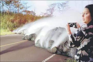  ?? – Reuters photo ?? A news reporter takes pictures of the Kilauea lava flow that crossed Pohoiki Road near Highway 132, near Pahoa, Hawaii, US on May 28.