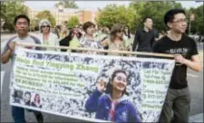  ?? HOLLY HART — THE NEWS-GAZETTE VIA AP, FILE ?? In this file photo, Yingying Zhang’s father Ronggao Zhang, left, and her friend Xiaolin Hou carry the banner as community members join together to walk for Yingying, a Chinese scholar who went missing three weeks ago in Urbana, Ill.