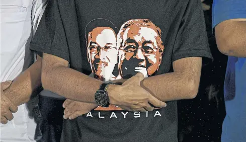  ?? REUTERS ?? A supporter wearing a T-shirt showing Malaysian politician Anwar Ibrahim and Prime Minister Mahathir Mohamad attends a rally in Kuala Lumpur.