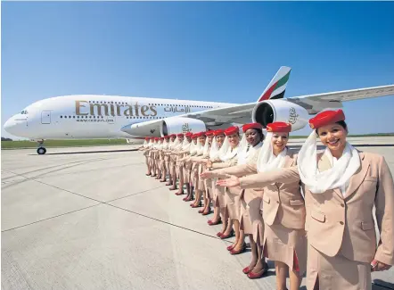  ??  ?? Emirates crew members stand beside an A380 superjumbo. The airline wants to spur Thai arrivals to the home base in Dubai.