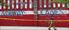  ?? MIKE CARDEW / BEACONJOUR­NAL ?? Firefighte­r Tyler Simcox walks past Midway Lanes in Akron on Wednesday after a fire there Tuesday night. The bowling alley, which had been a recreation­al fixture for more than 50 years, closed in June 2014 when its owners merged operations with Stonehedge Family Fun Center on North Hill.