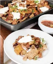  ?? KATE KRADER Bloomberg News ?? Make sure to use thick tortilla chips that won’t collapse when the seafood-studded chili is spooned on. Garnish with sour cream and scallions.