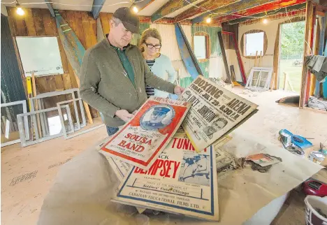  ?? ARLEN REDEKOP ?? Jeremy and Sus Borsos look over old posters inside the Blue Cabin on Monday. The posters were found underneath the floorboard­s of the former squatter shack, now at Maplewood Farm in North Vancouver, which is being renovated and turned into an artist’s...