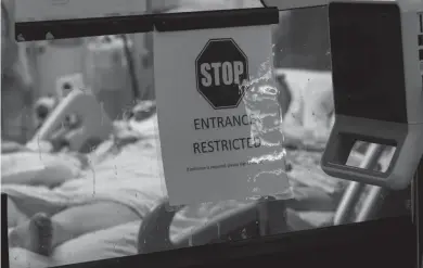  ?? MARK HOFFMAN/MILWAUKEE JOURNAL SENTINEL ?? A COVID-19 patient on a ventilator lies in a negative air pressure room in a 12-bed intensive care unit at UW Hospital in Madison on Thursday.