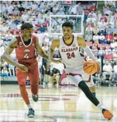  ?? BRANDON SUMRALL/GETTY ?? Alabama’s Brandon Miller, right, drives against Arkansas’ Davonte Davis on Saturday at Coleman Coliseum in Tuscaloosa, Alabama.