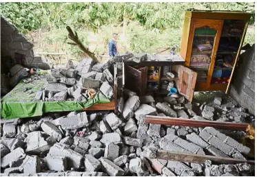  ?? — Reuters/AFP ?? All that’s left: A damaged house is seen after the earthquake in Sajang village, Lombok Timur, Indonesia. (Below) Indonesian President Joko Widodo visiting affected residents at a shelter in Lombok.