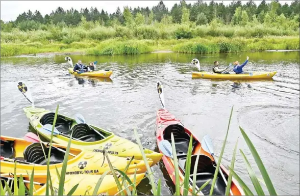  ??  ?? Journalist­s take in kayaks along the Uzh river in the Chernobyl exclusion zone in Ukraine, as a tourist firm presents the newly created river tours. The hit US drama brought tourists to the nuclear disaster zone, but guides say many visitors are more interested in taking selfies or even stealing artefacts than learning about the accident.