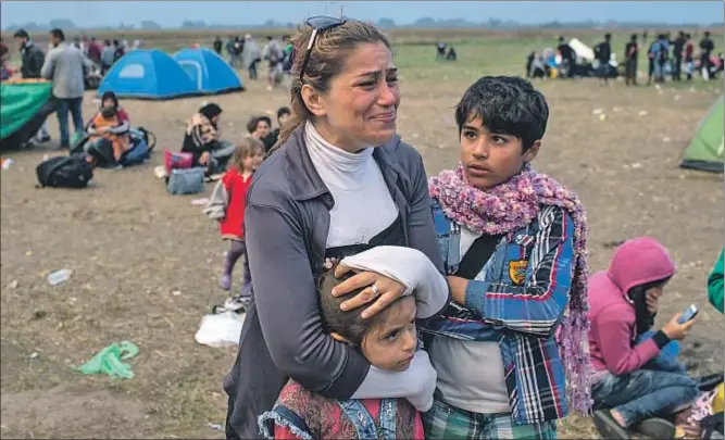  ?? MARKO DJURICA / REUTERS ?? Una mujer llegada de Siria llora junto a sus hijos en un campamento improvisad­o en Hungría, cerca de Roszke, después de cruzar la frontera desde Serbia