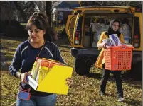  ?? ?? Maryam Aytac, a community member and volunteer coordinato­r (left) and Shaista Amani, economic empowermen­t coordinato­r for the Refugee Women’s Network, help unload donated goods for Afghan refugee families at Amani’s office in Decatur.