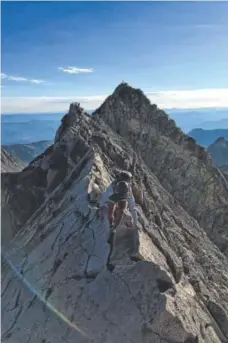  ?? Mary Cryan, Special to The Denver Post ?? Mary Cryan navigates Knife Edge on her way to summiting Capitol Peak (14,131 feet) on Aug. 27. The summit of K2 (13,664 feet) rises in the background.