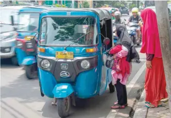  ?? — AFP ?? Indonesian women trying to haggle for a good price before using a three-wheeled bajaj taxi in Jakarta.