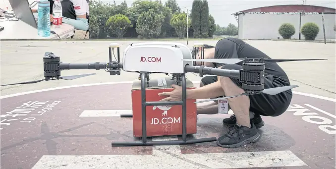  ??  ?? RIGHT Final adjustment­s are made to a JD.com delivery drone before the test flight.