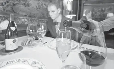  ?? STEVE HELBER/AP ?? Champagne is poured at a table where mannequins provide social distancing at the Inn at Little Washington as the restaurant prepares in May to reopen in Washington, Virginia. A new relief package restores tax breaks for business meals at restaurant­s.